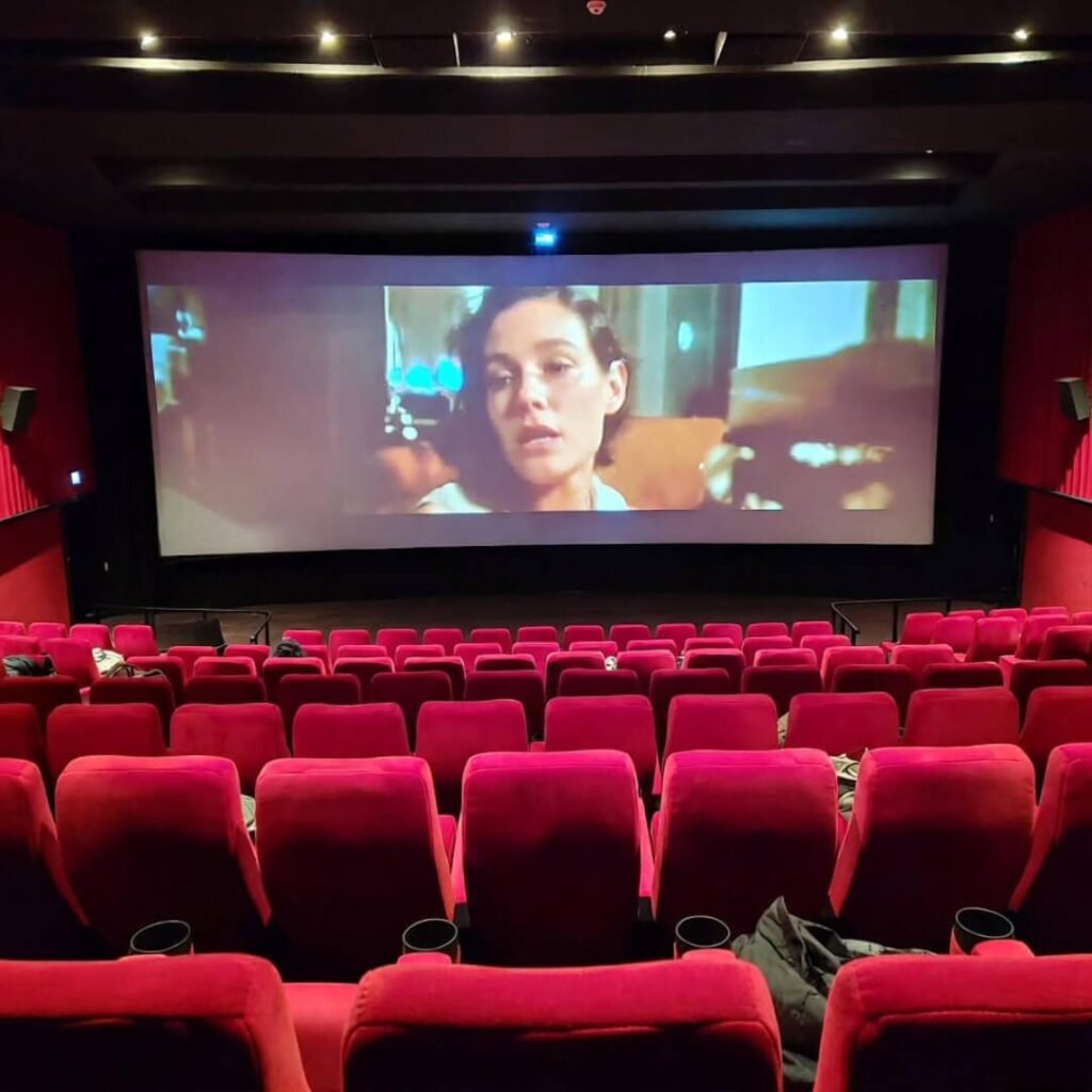 Dimly lit classic red cinema auditorium showing film.